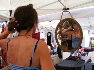 A market patron admires a necklace from Jewels in Bloom