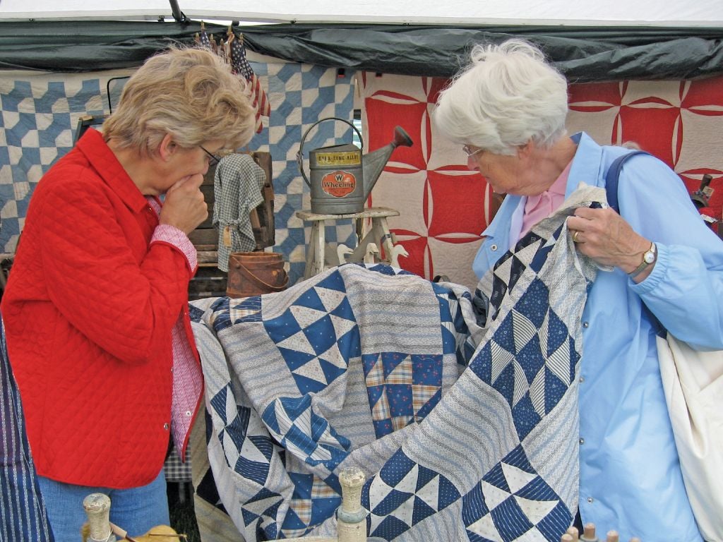 Two women look at the pattern of a quilt at Shipshewana Antique Market